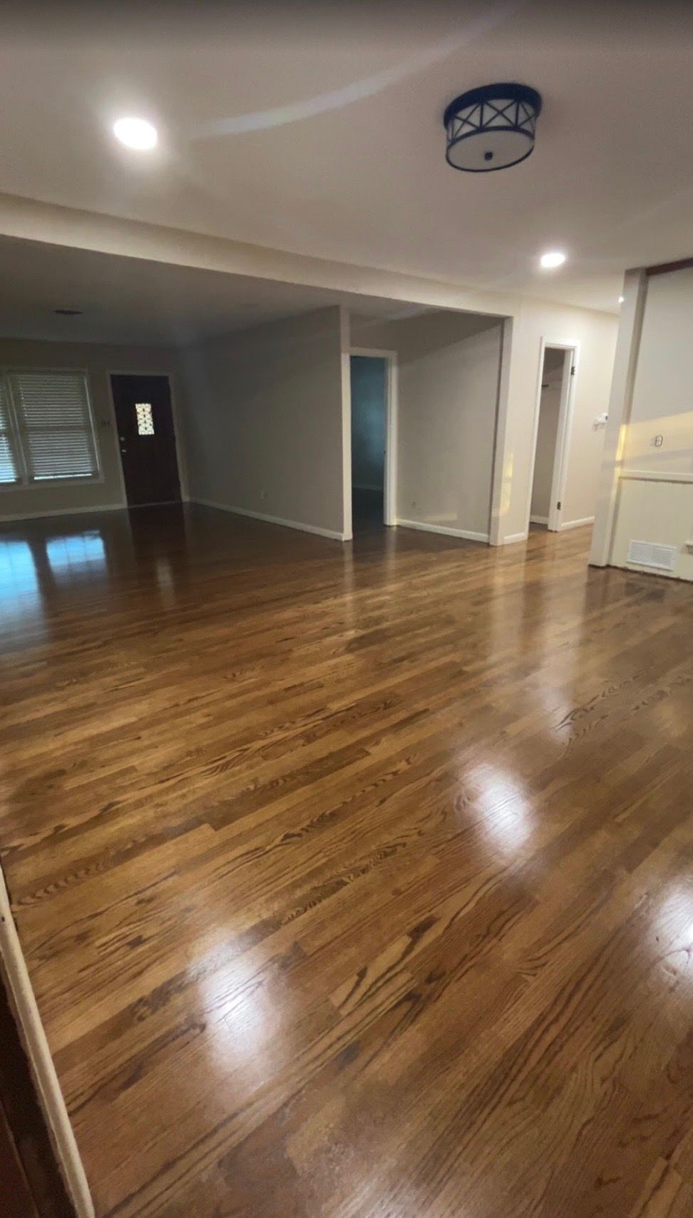 Hardwood floors in a renovated living space. Includes recessed lights, ceiling fixture, and neutral-colored walls.