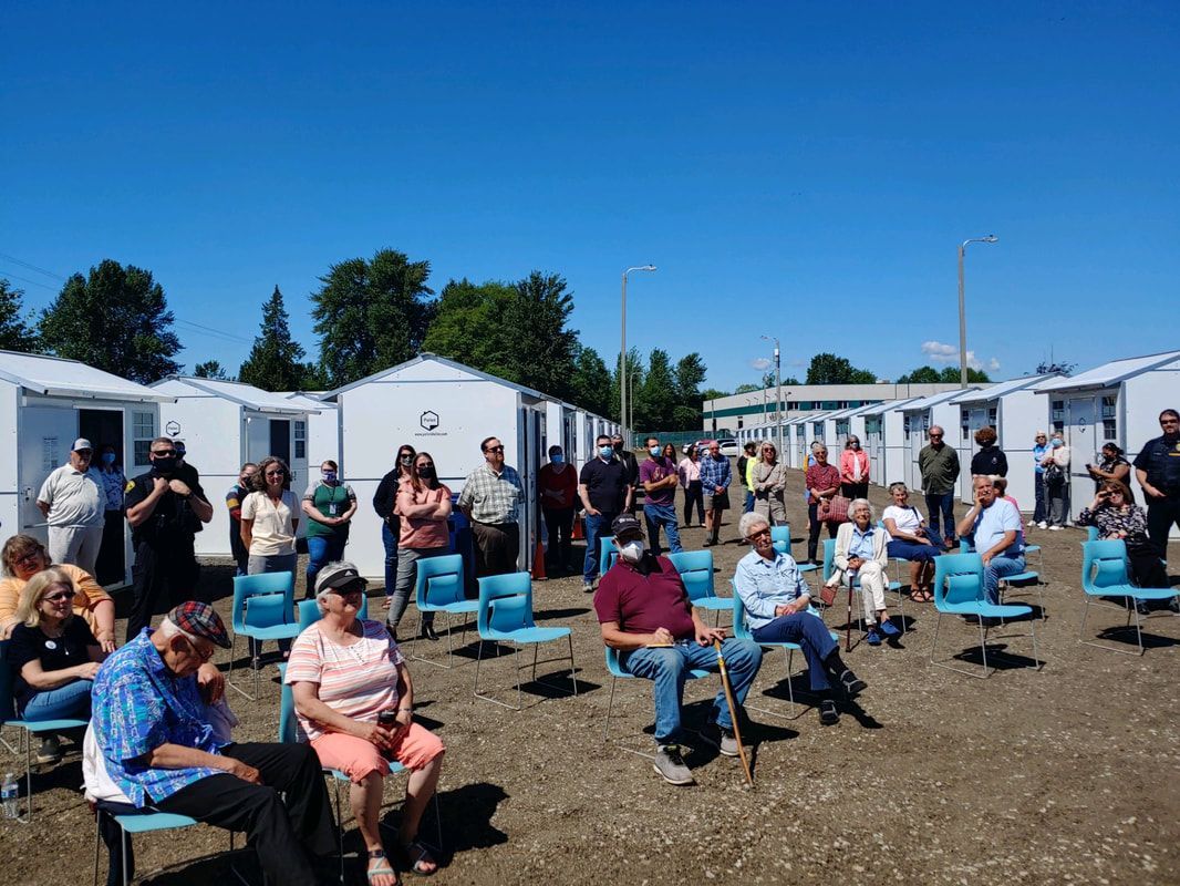 A group of people are sitting in chairs in a field.