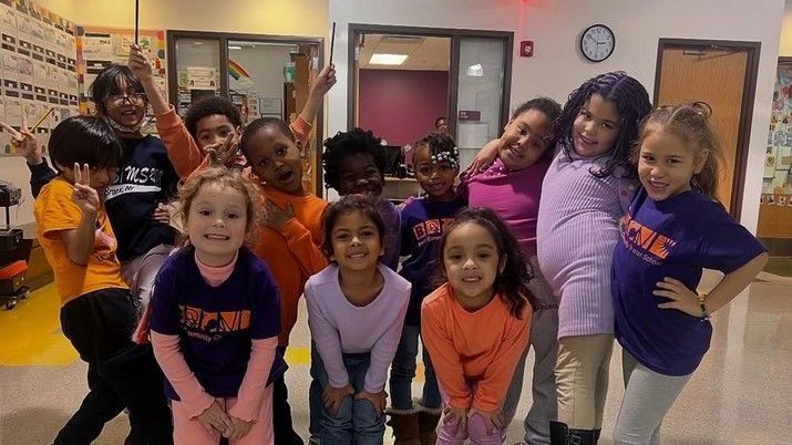 A group of children are posing for a picture in a hallway.