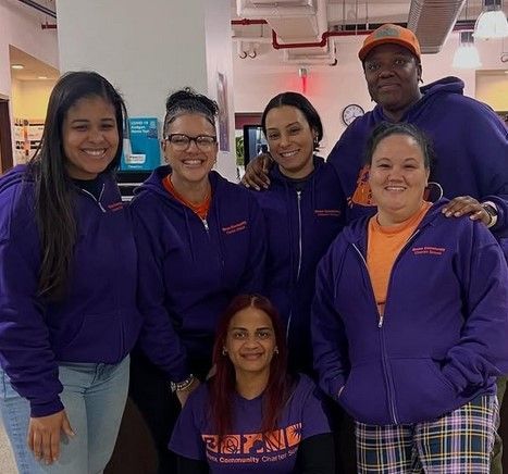 A group of people wearing purple hoodies are posing for a picture.
