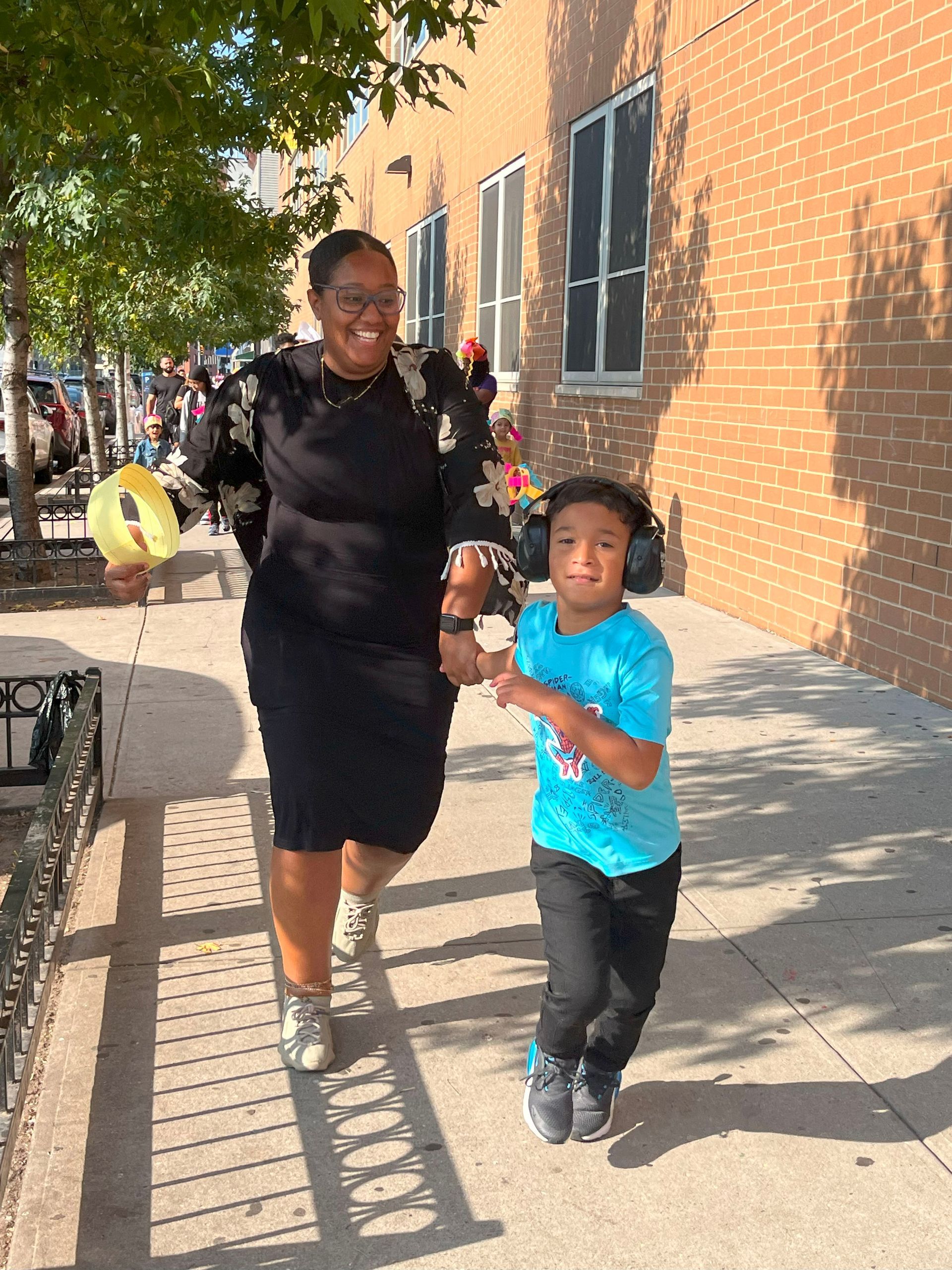A woman and child are walking down a sidewalk holding hands