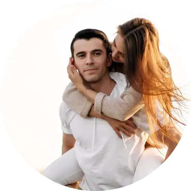 Couple embracing on a white background, woman kissing man’s cheek