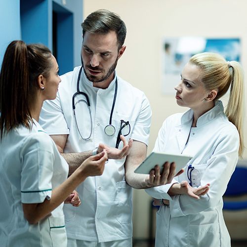 Doctors in white coats discussing patient notes in a hospital corridor