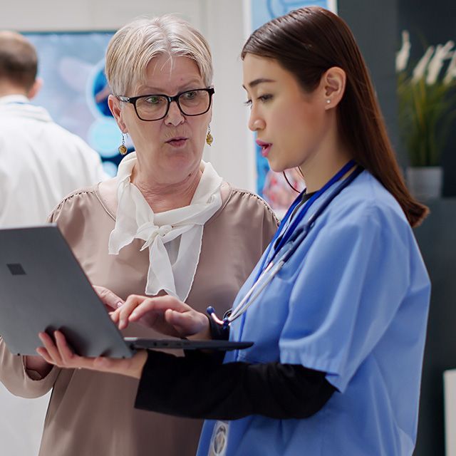 Two clinicians reviewing a laptop together in a hospital setting
