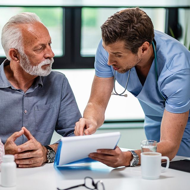 Doctor explaining a tablet to a patient at a desk in a bright clinic