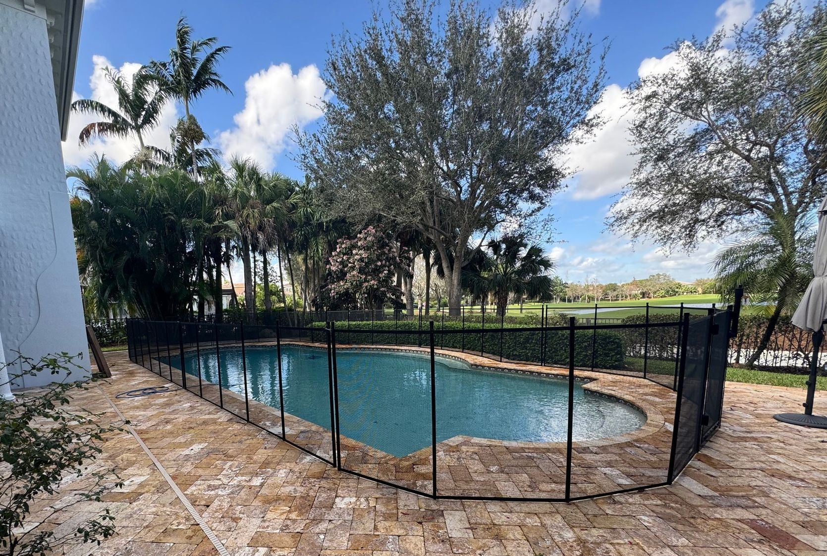 a large swimming pool surrounded by a fence and a patio .