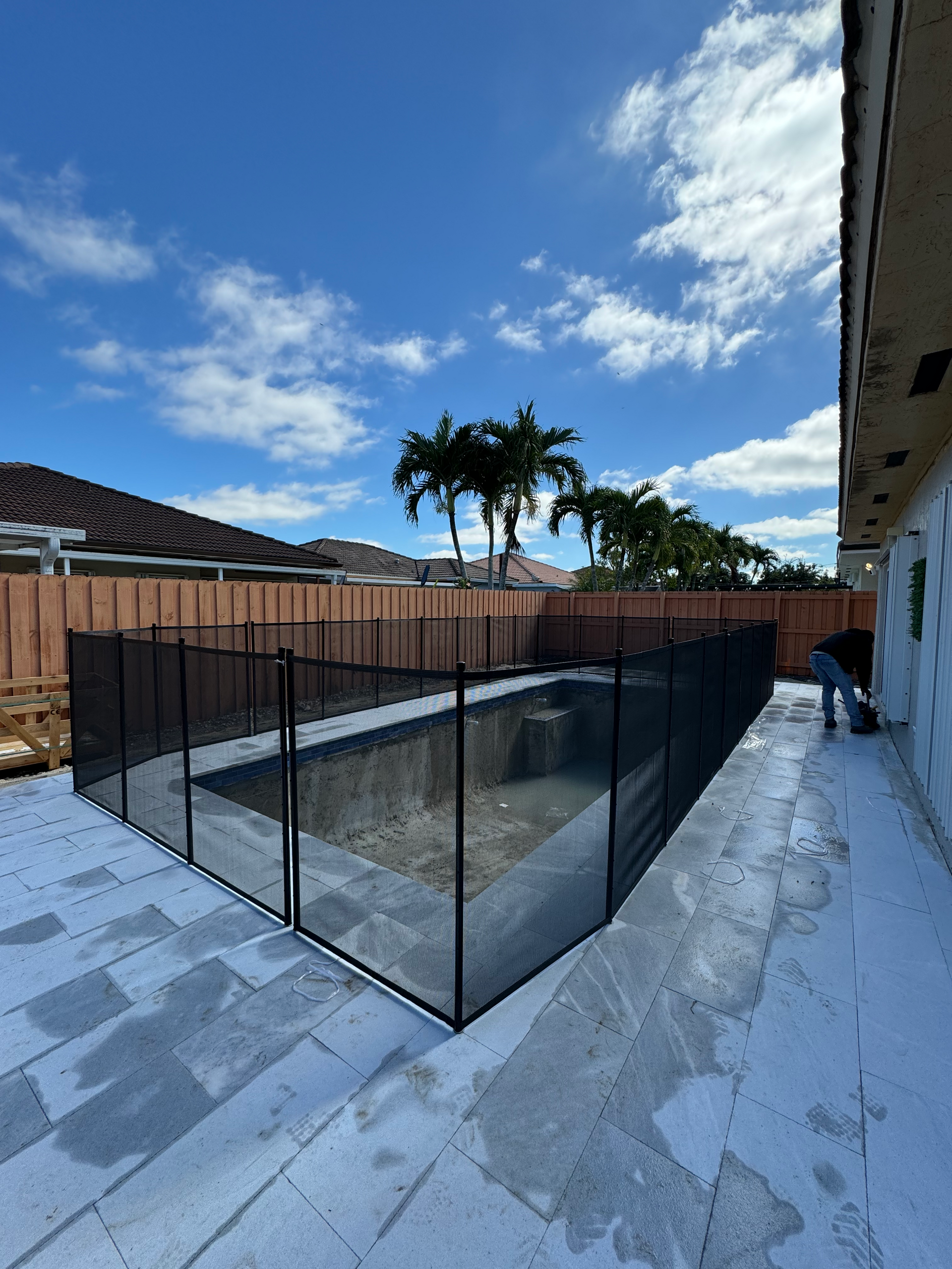 a swimming pool with a fence around it and palm trees in the background