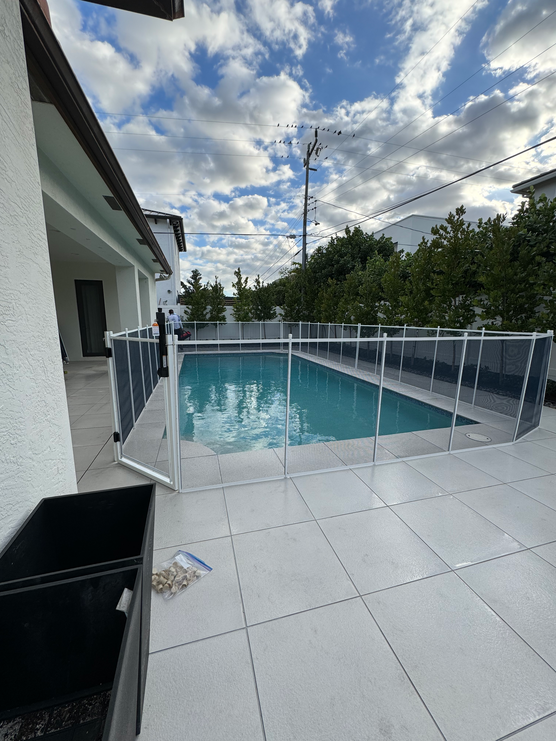 a large swimming pool is surrounded by a fence in front of a house .