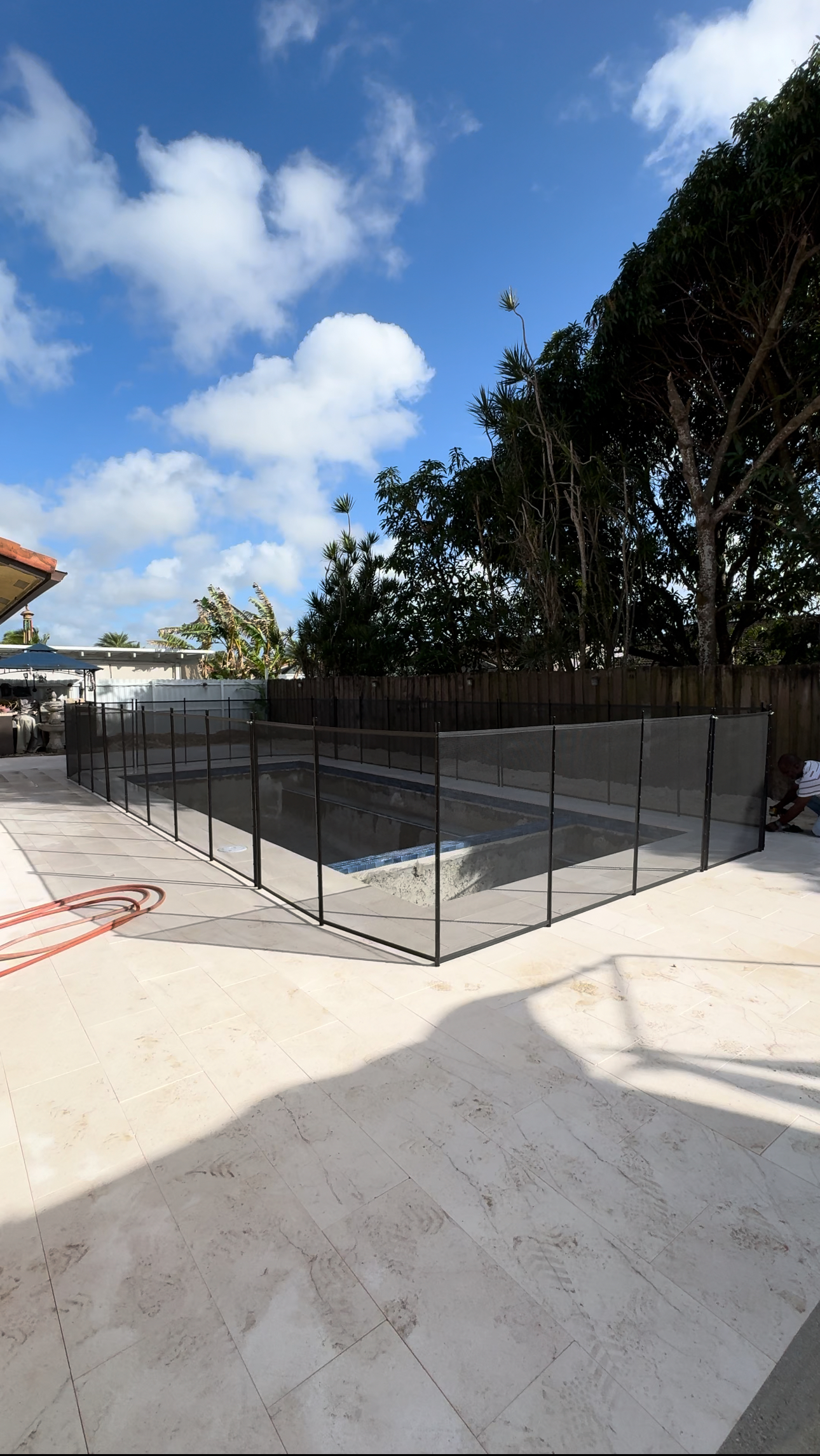 a fence surrounds a swimming pool in a backyard .
