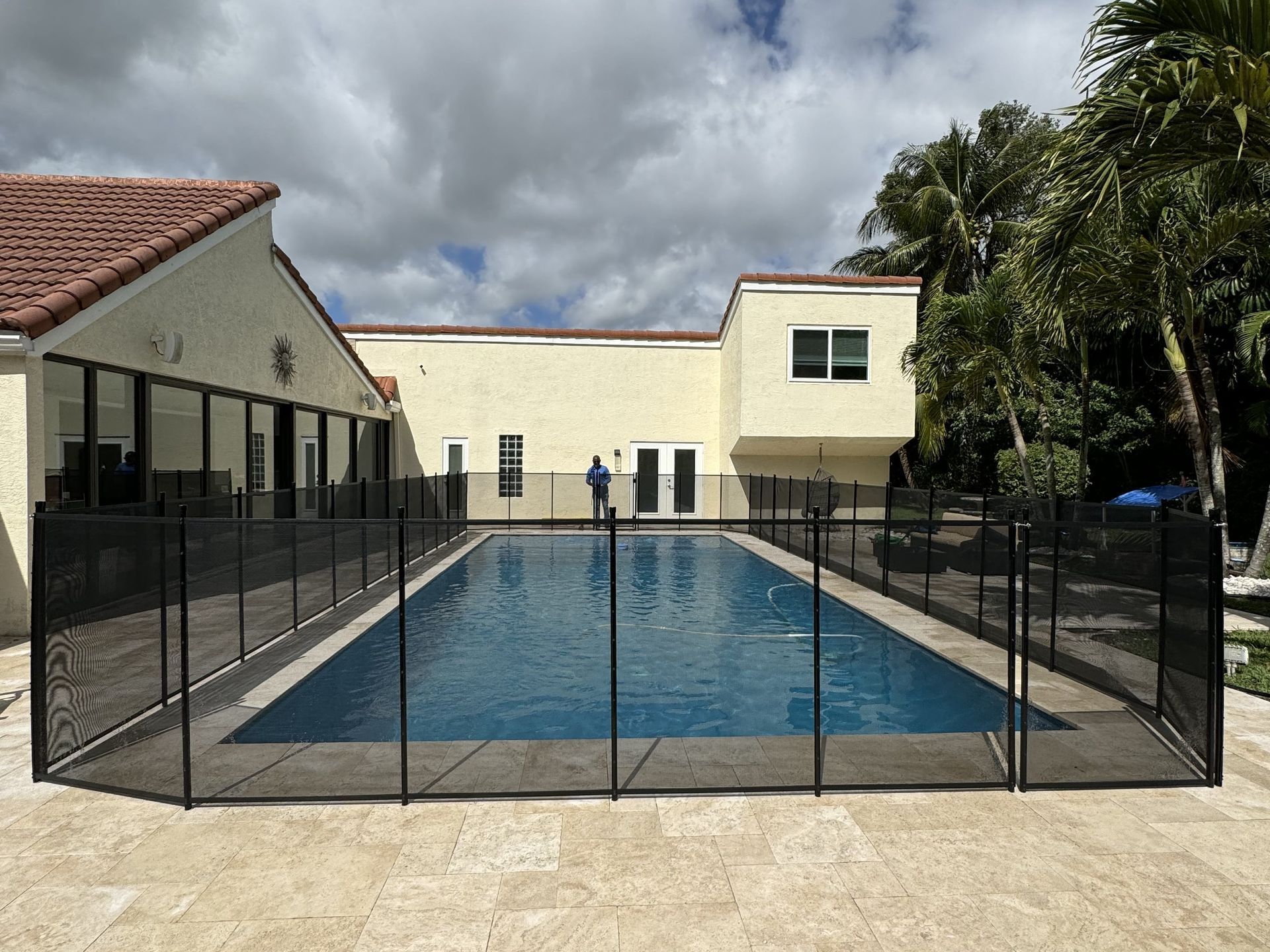 A large swimming pool with a fence around it in front of a house.
