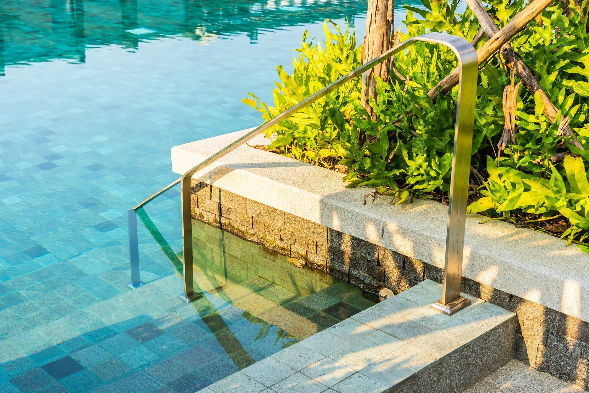 a staircase leading to a swimming pool with a stainless steel railing .