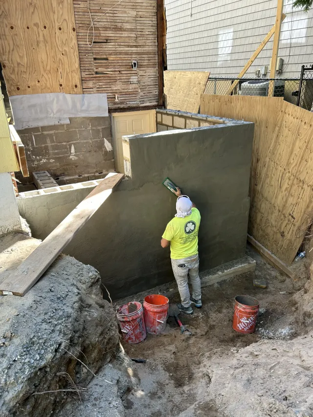 Construction worker plastering a concrete wall in a basement excavation site