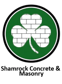 Shamrock Concrete & Masonry logo with green shamrock outlined in black and white brick pattern inside circle