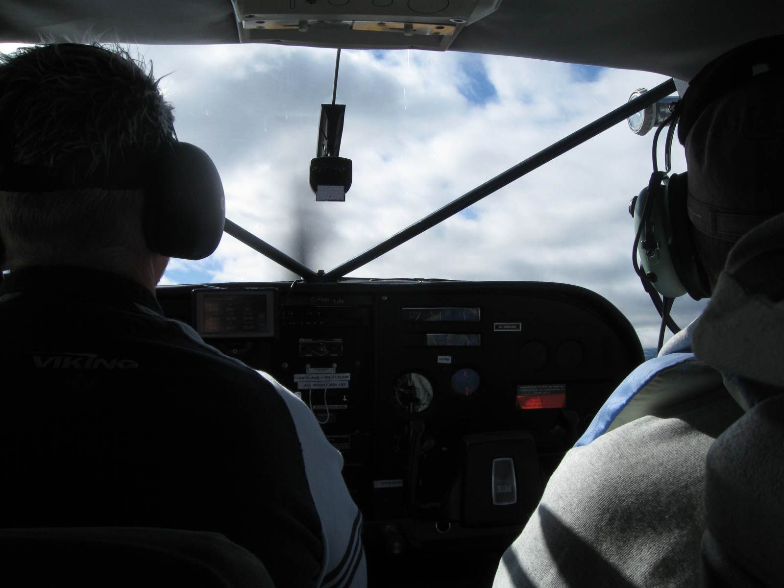 Cockpit view of two pilots flying, looking out at cloudy sky through the windshield