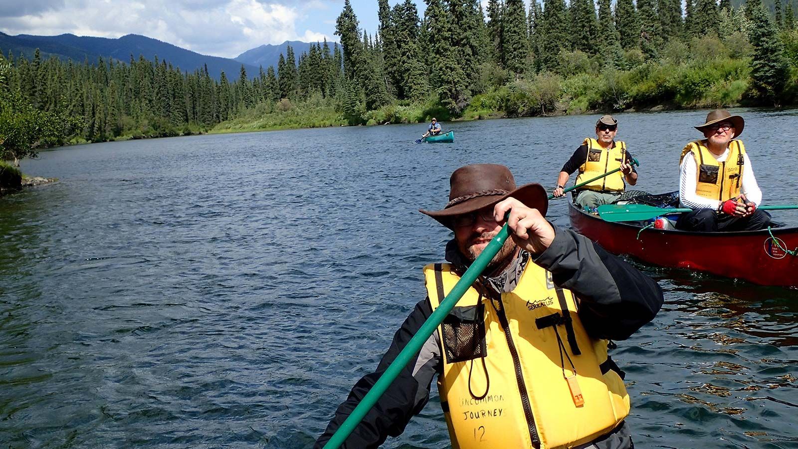 Kayakers paddling on a lake with forested mountains in the background