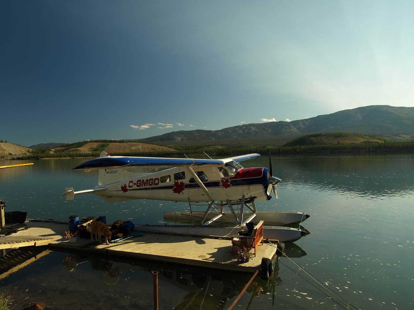 Seaplane docked on a floating pier on a calm lake with mountains in the background