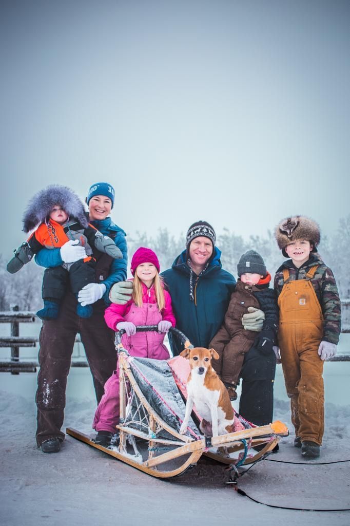 Family posing with a sled in a snowy winter landscape