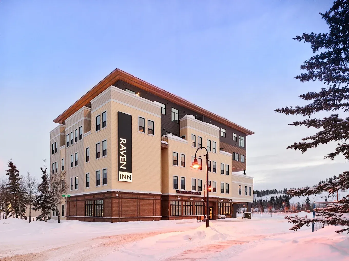Modern hotel rendering with brown and white facade, street-level entrance, and trees at the corner.