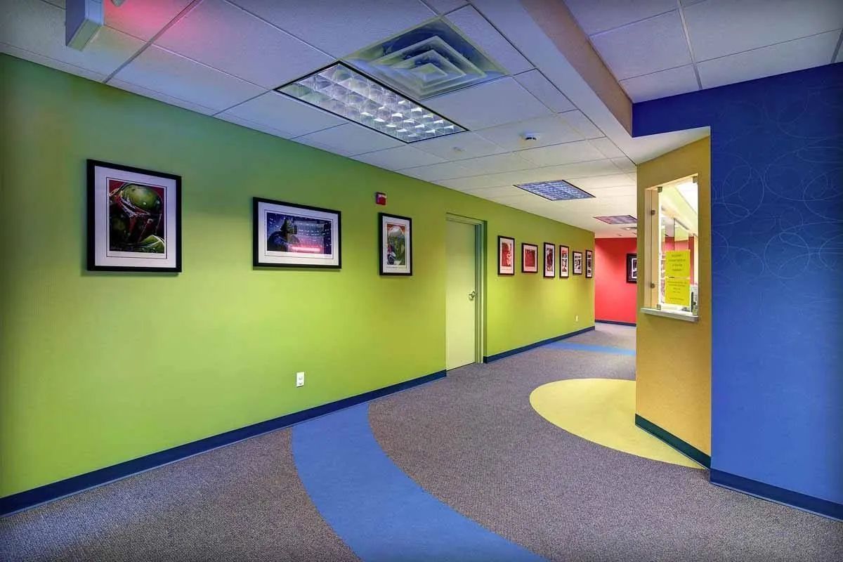 A hallway with green and blue walls and a blue carpet