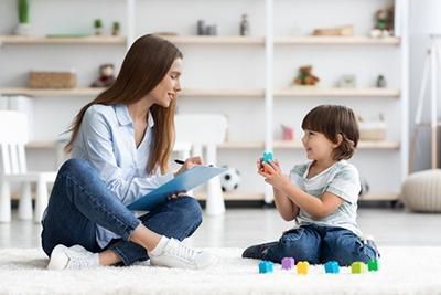 A woman is sitting on the floor talking to a child.