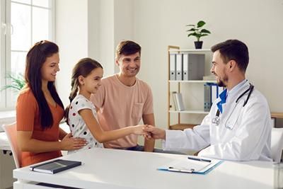 A doctor is shaking hands with a family in a doctor 's office.