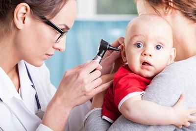 A doctor is examining a baby 's ear with an otoscope.