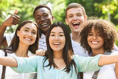 A group of young people are posing for a picture in a park.