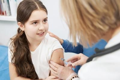 A little girl is getting an injection in her arm from a doctor.