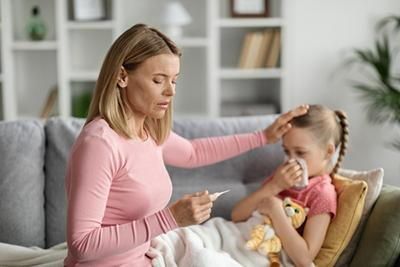 A woman is taking the temperature of a sick little girl.
