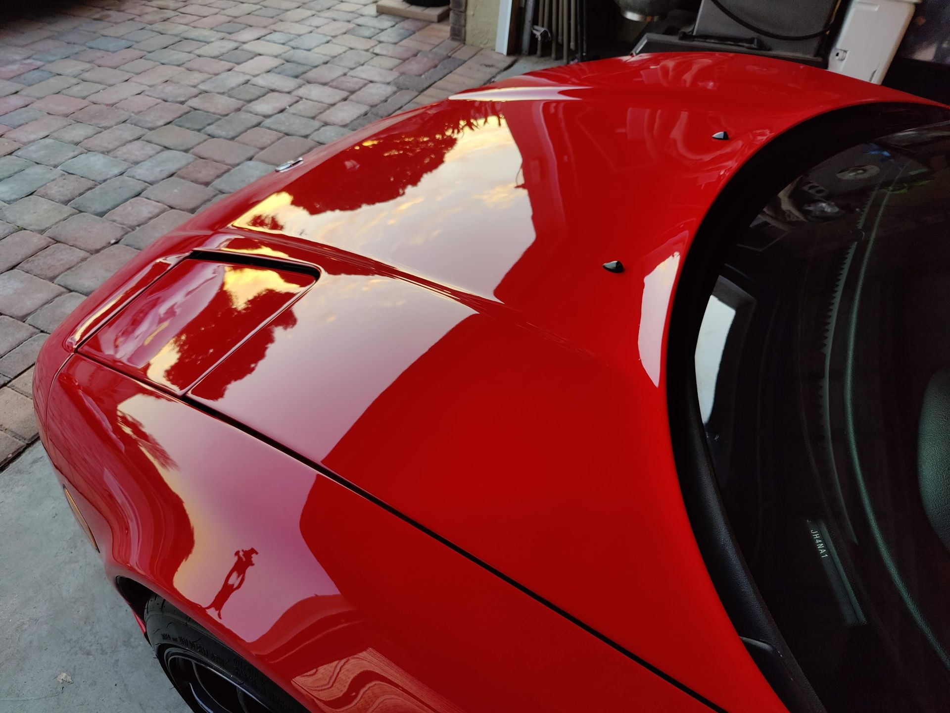 a red car is parked on a brick driveway