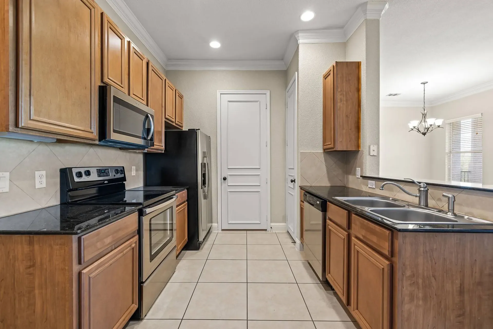 Modern kitchen with stainless steel appliances, granite countertops, and wood cabinetry.