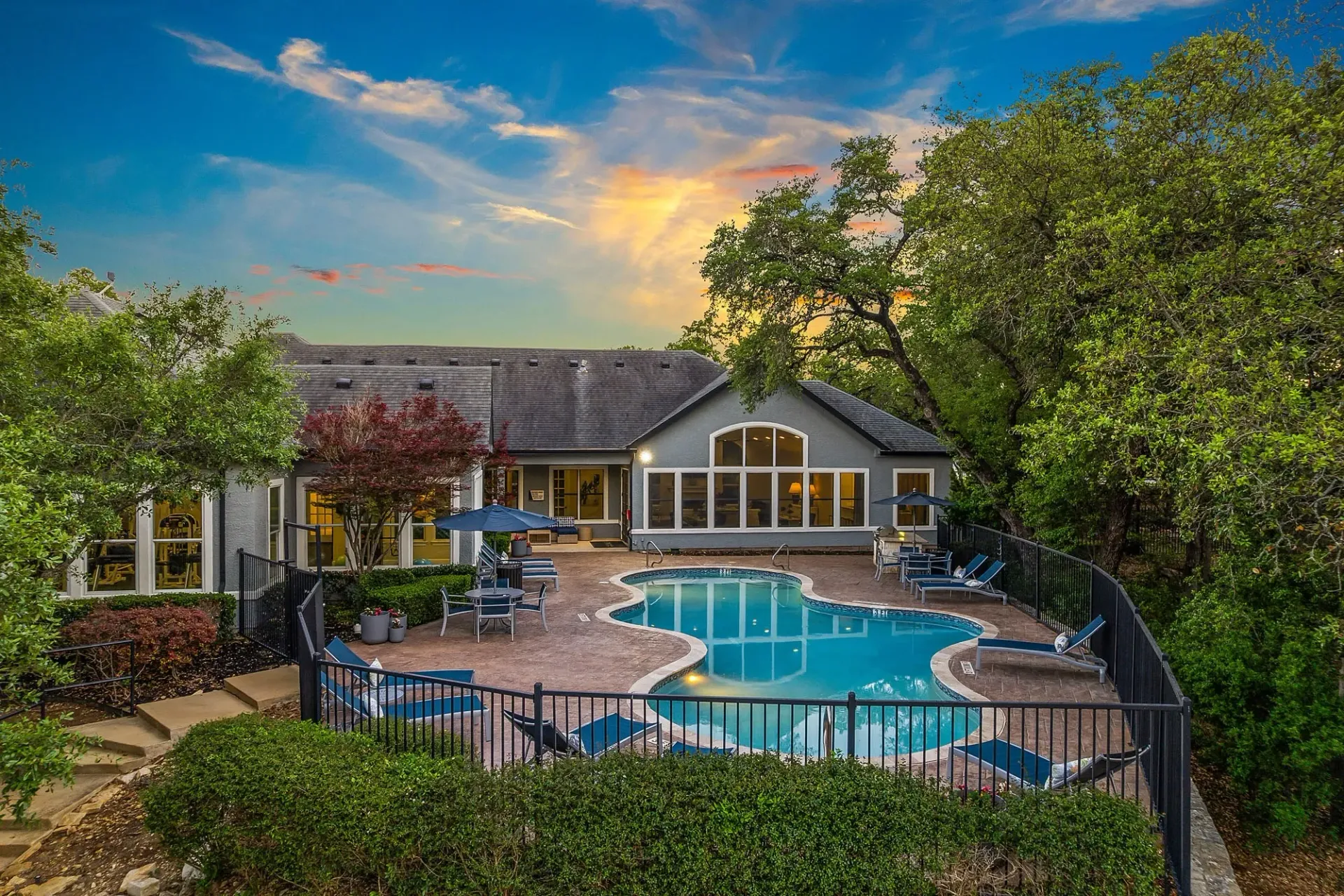 Resort-style swimming pool and sun deck with lounge chairs and umbrellas.