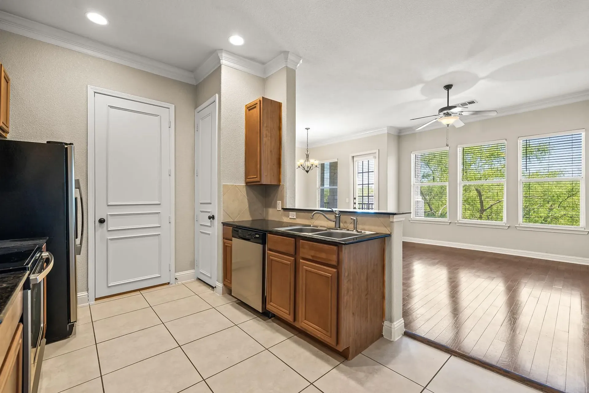 Kitchen with wooden cabinets, stainless steel appliances, and a view into the living area with large windows.
