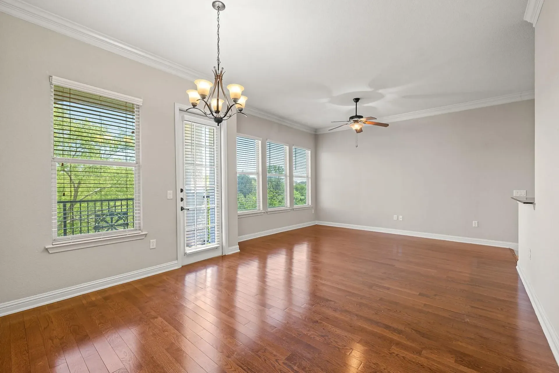 Spacious living room with hardwood floors, large windows, and a balcony door.