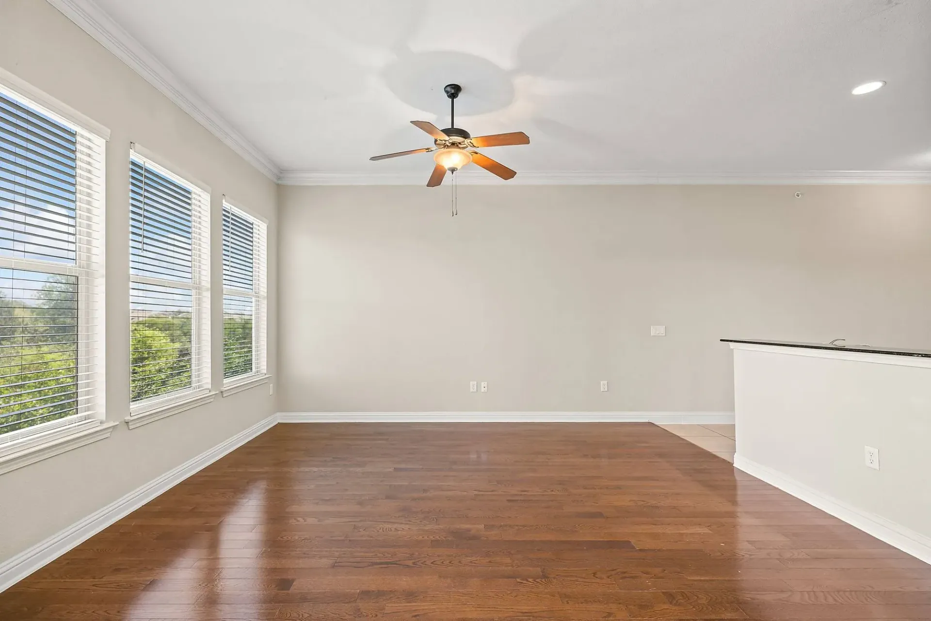 Empty living room with hardwood floors and large windows.