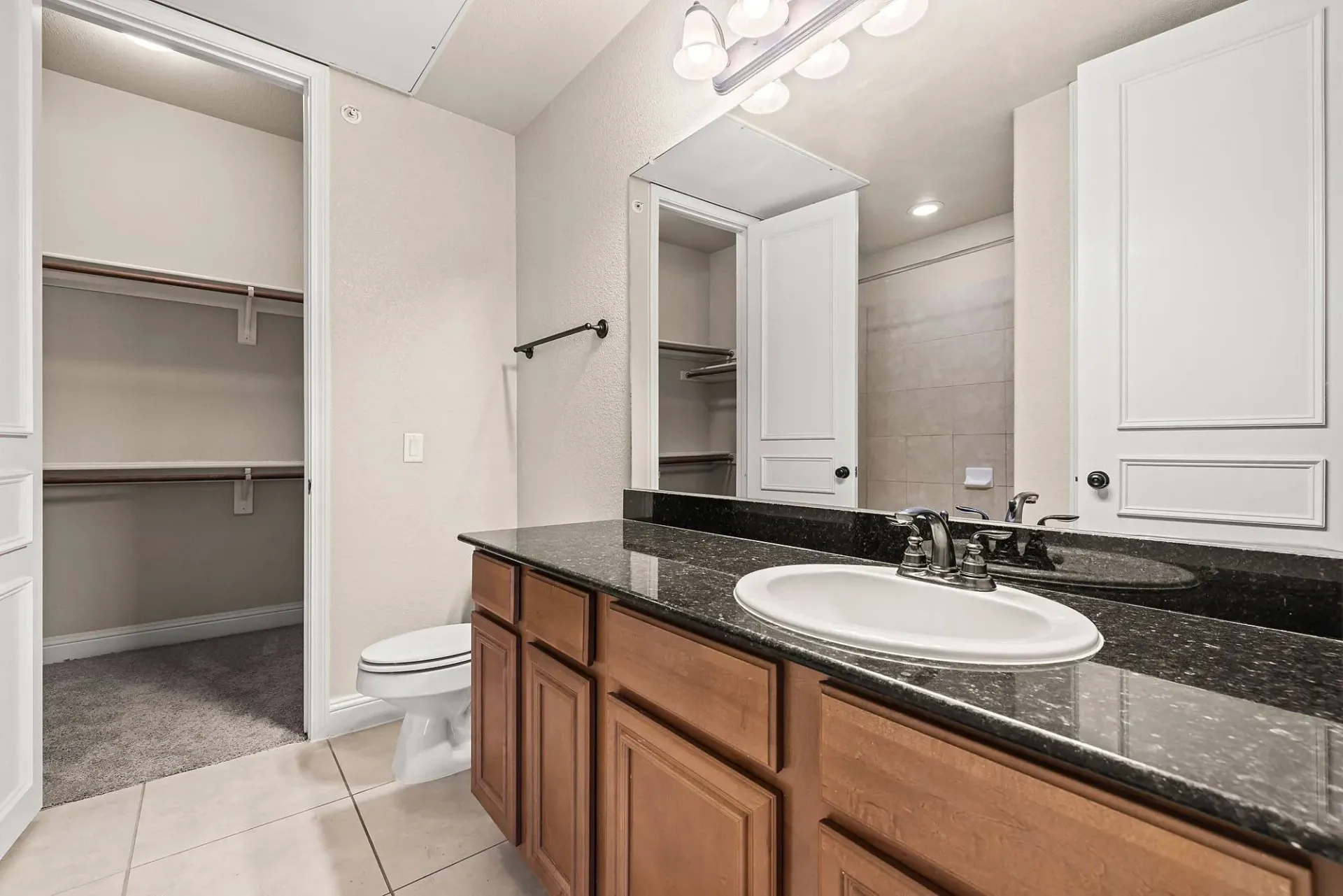 Bathroom with a vanity, sink, toilet, and walk-in closet.