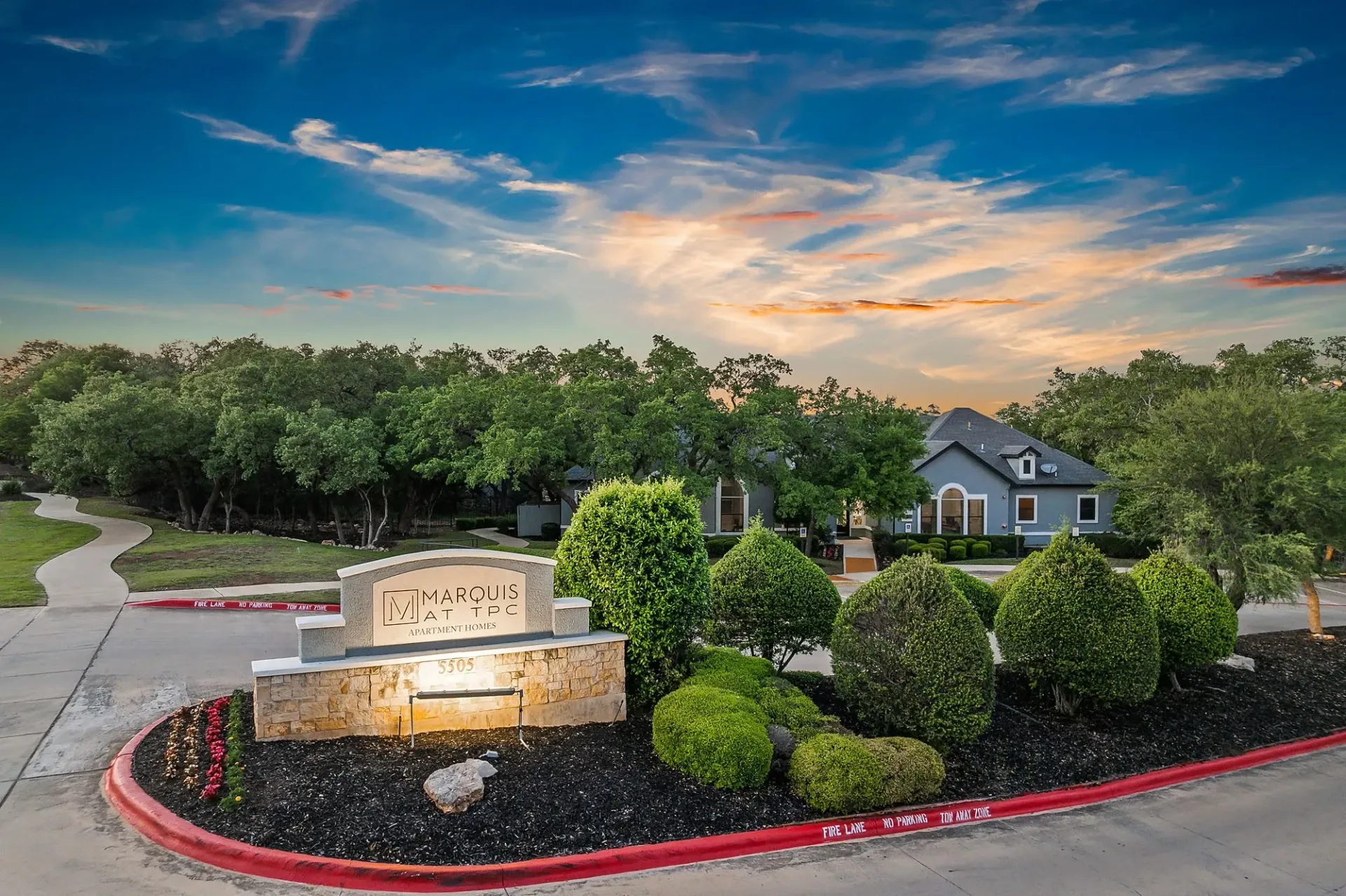 Marquis at TPC Apartment Homes monument sign and entrance with landscaping and building in background