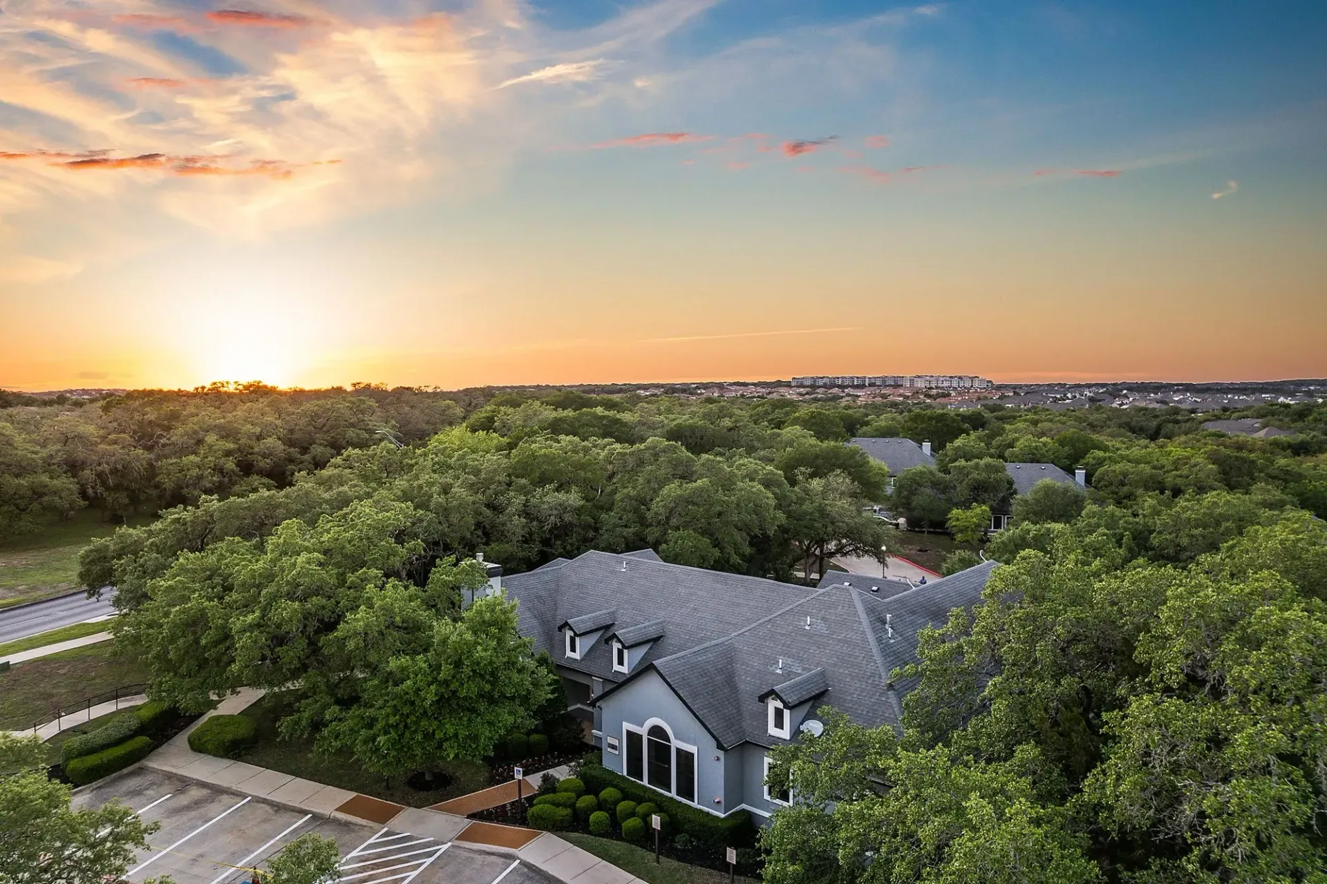 Apartment complex surrounded by trees at sunset.