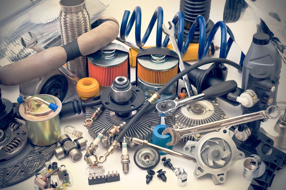 Car parts, including filters, springs, hoses, and other components, are arranged on a white surface.