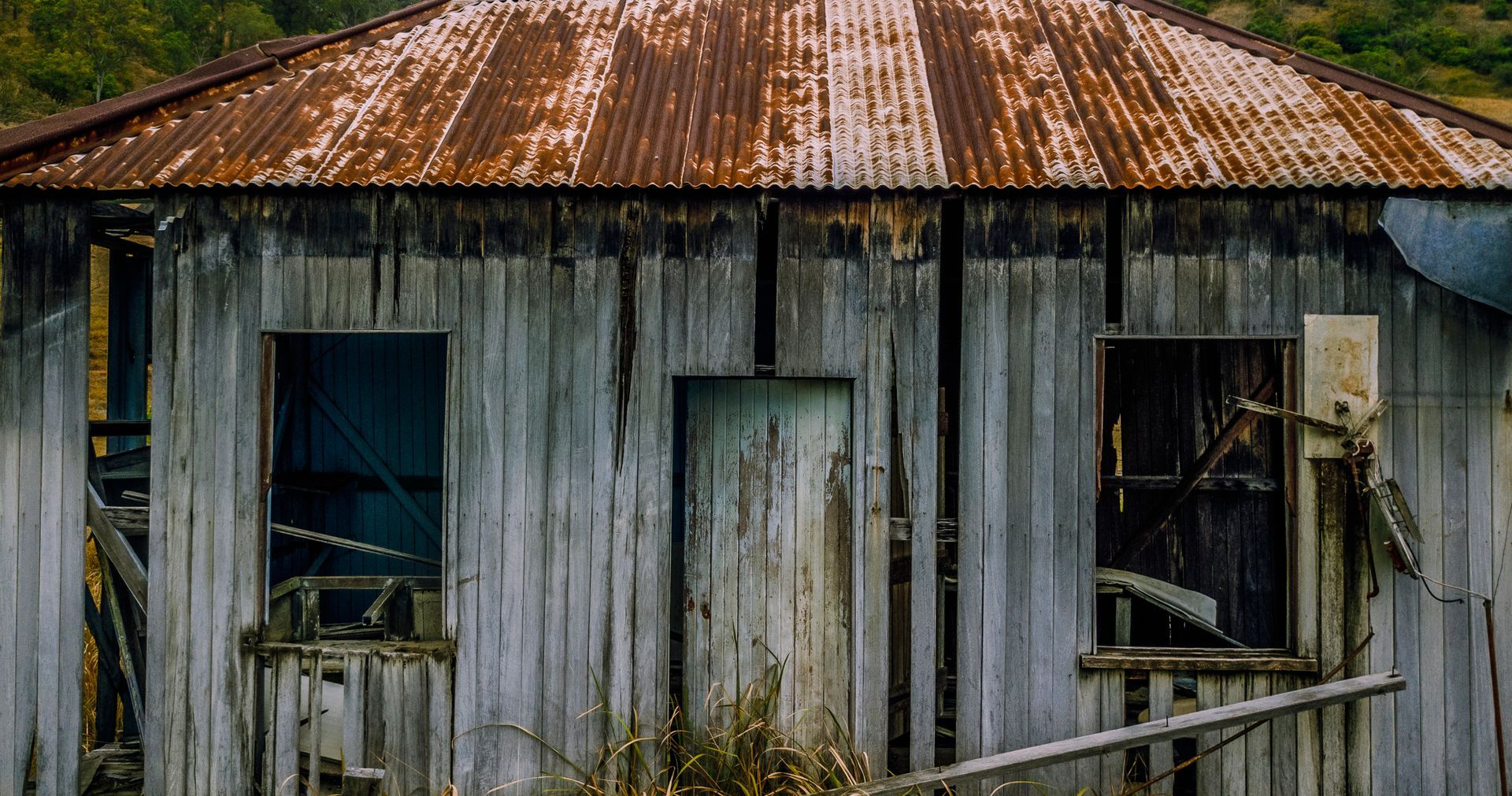 An old wooden house with a rusty tin roof.
