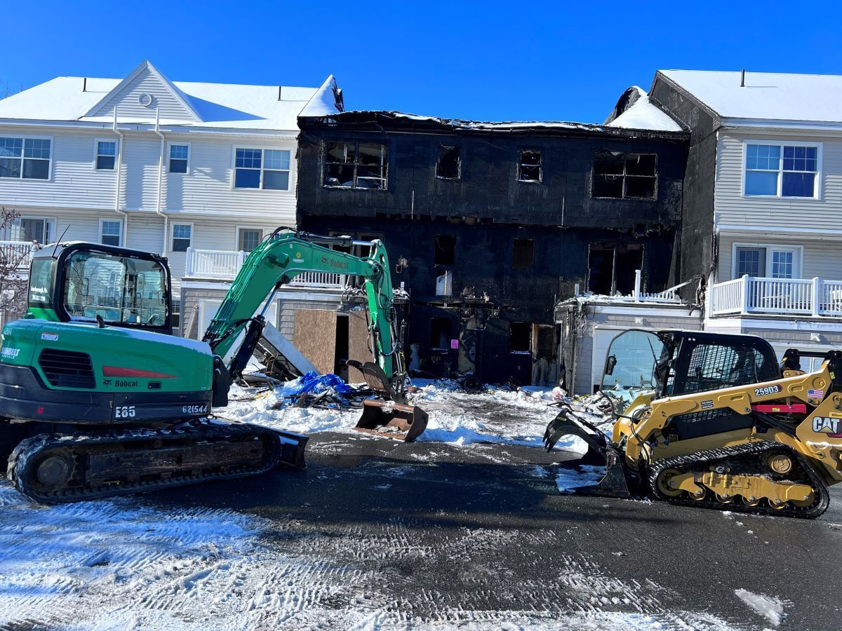 Burned apartment building with excavators and debris after a fire