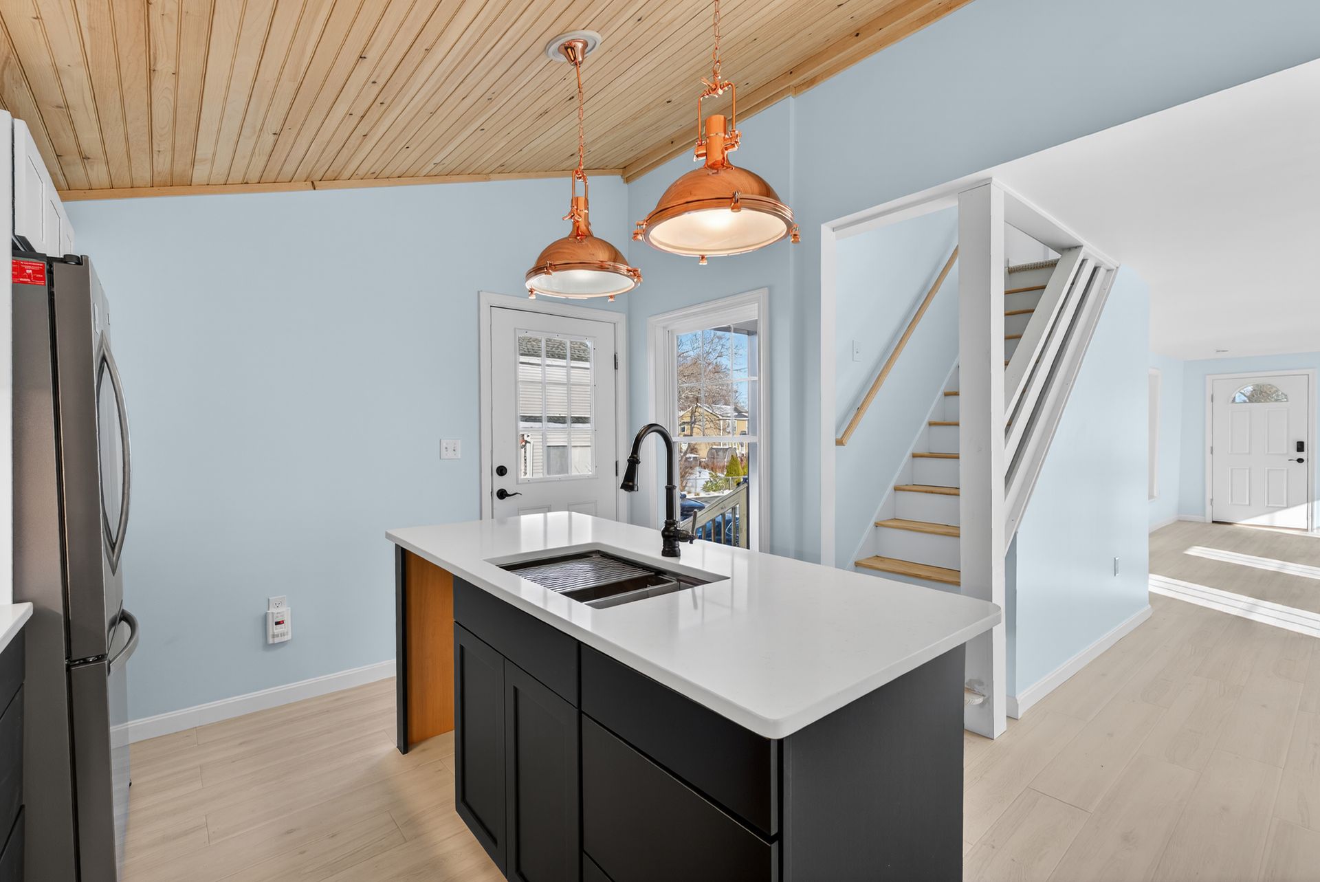 Kitchen with island, black cabinets, white countertop, copper pendant lights