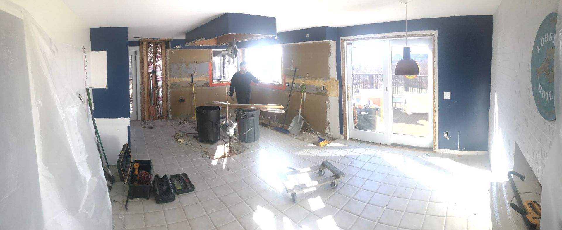 Bright, partially renovated room with tiled floor, tools, and sunlight through glass doors