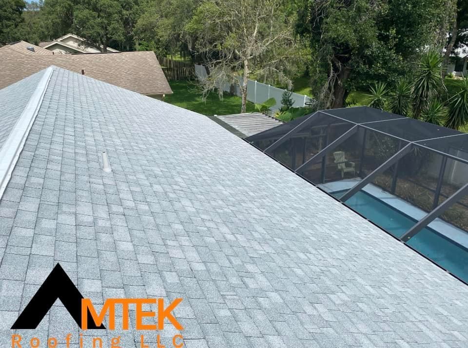 Gray shingle roof with screened pool enclosure and trees in the background