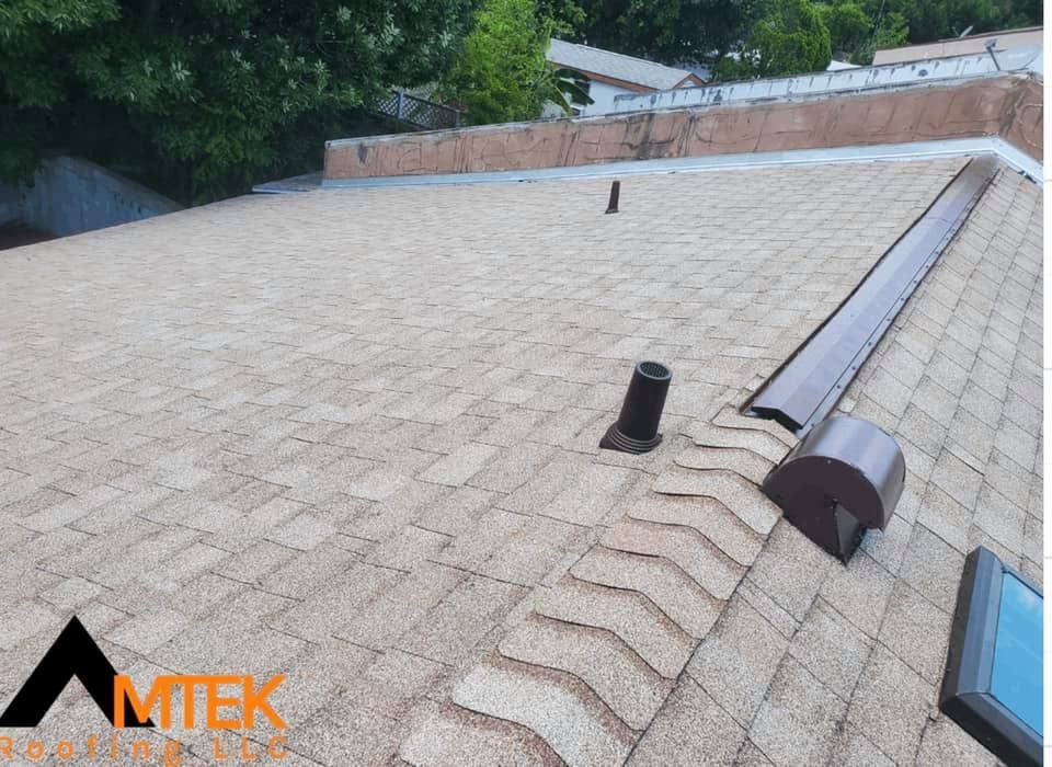 Roof with asphalt shingles, ridge vent, and two roof vents on a sloped residential roof.