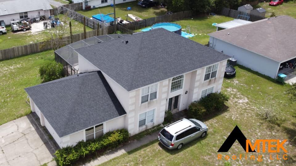 Aerial view of a two-story gray house with a driveway, parked SUV, and fenced yard with a pool and trampoline.