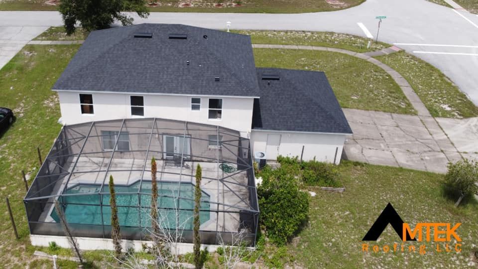 Aerial view of a two-story house with a screened-in pool enclosure and driveway