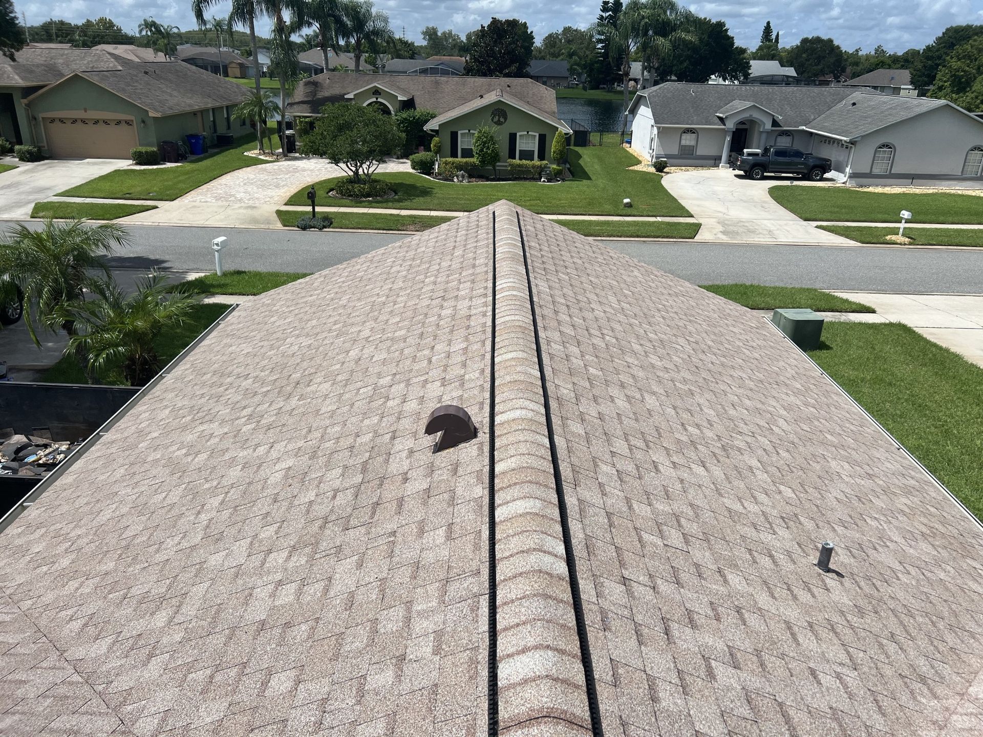 Hands securing shingles on a roof with a hammer and nail on a sunny day