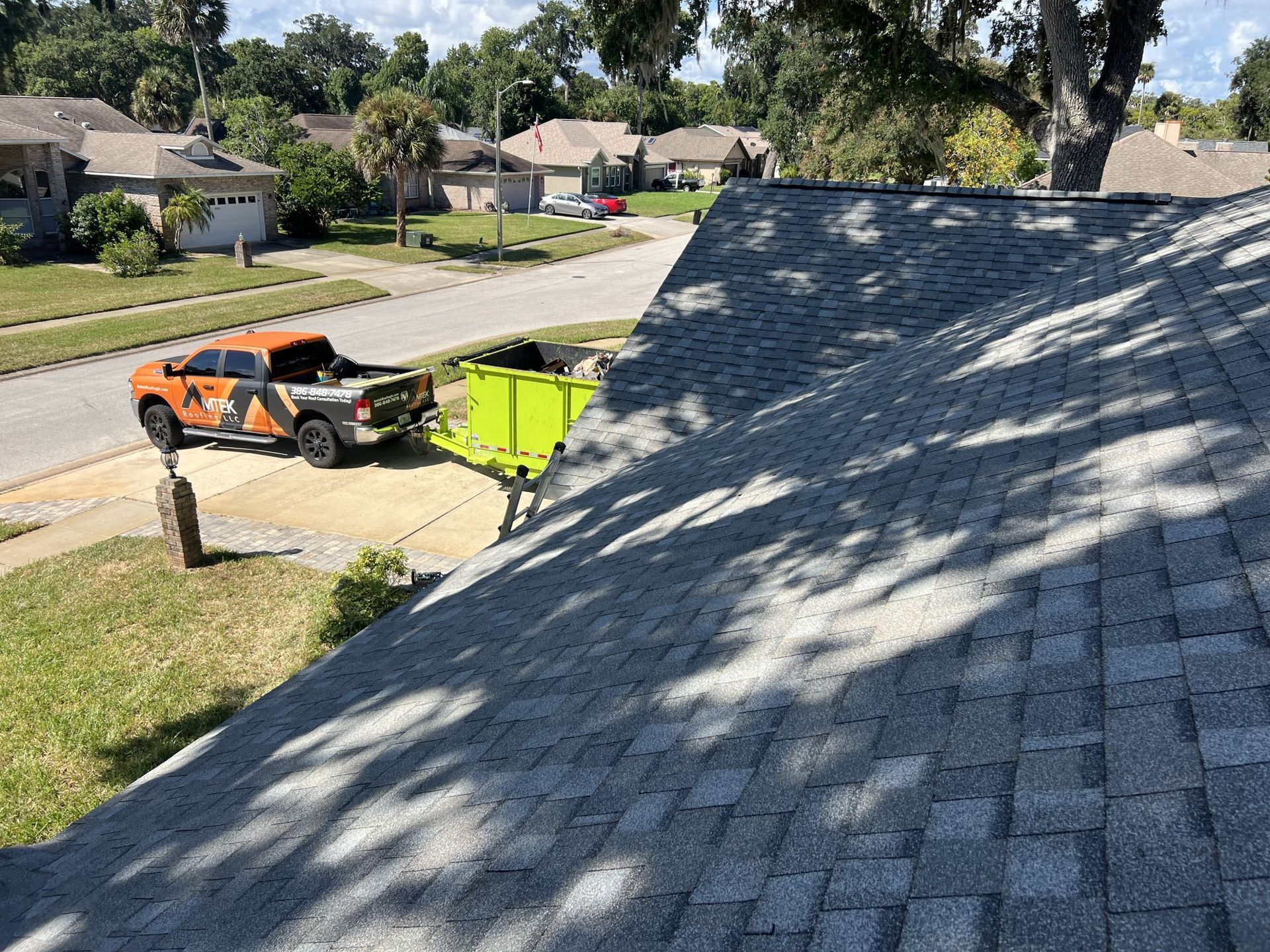 Person in a red shirt inspecting a white gutter on a house roofline outdoors
