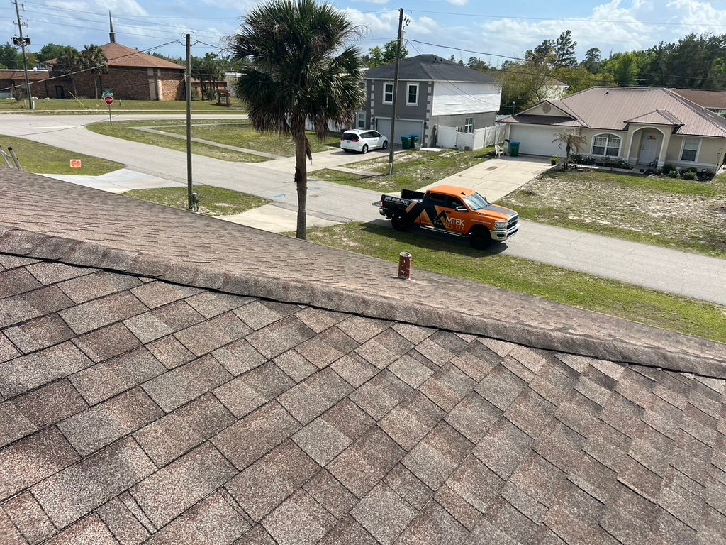 Orange car parked on a residential street beside houses and a sidewalk, viewed from a rooftop.